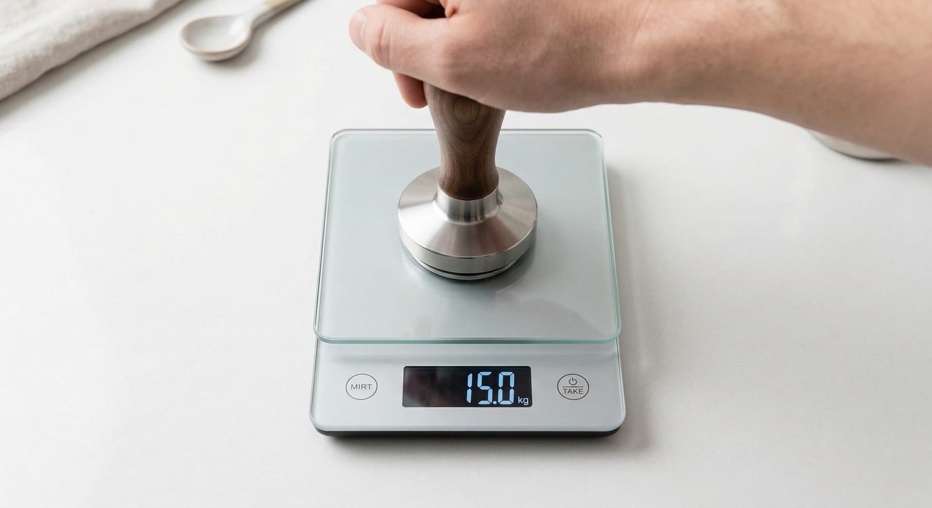 Espresso tamper being pressed down onto a digital kitchen scale showing 15 kg reading — pressure calibration technique for consistent espresso tamping
