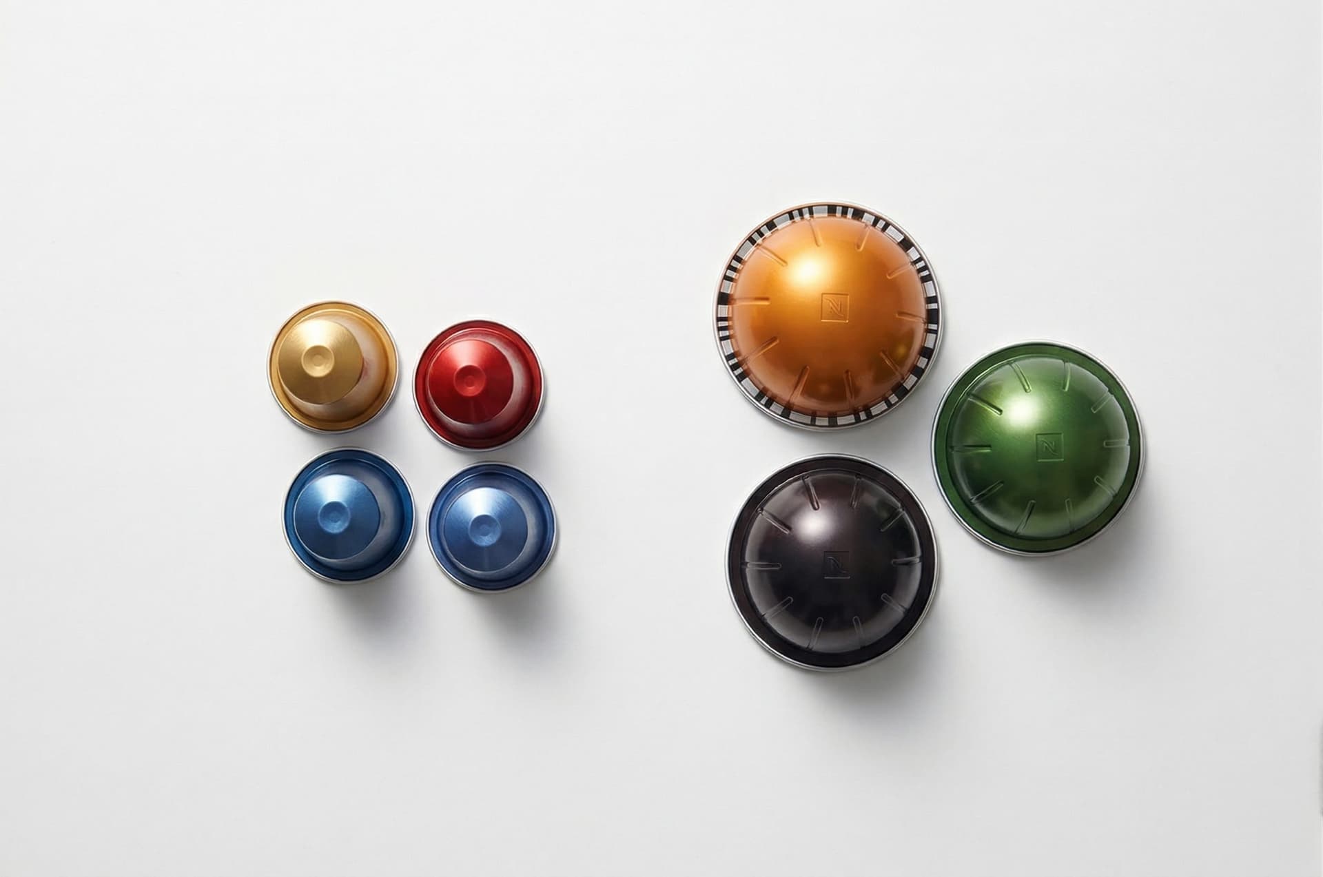 Original Line Nespresso capsules (small, conical) beside Vertuo capsules (large, dome-shaped) side by side — nespresso capsule comparison size difference