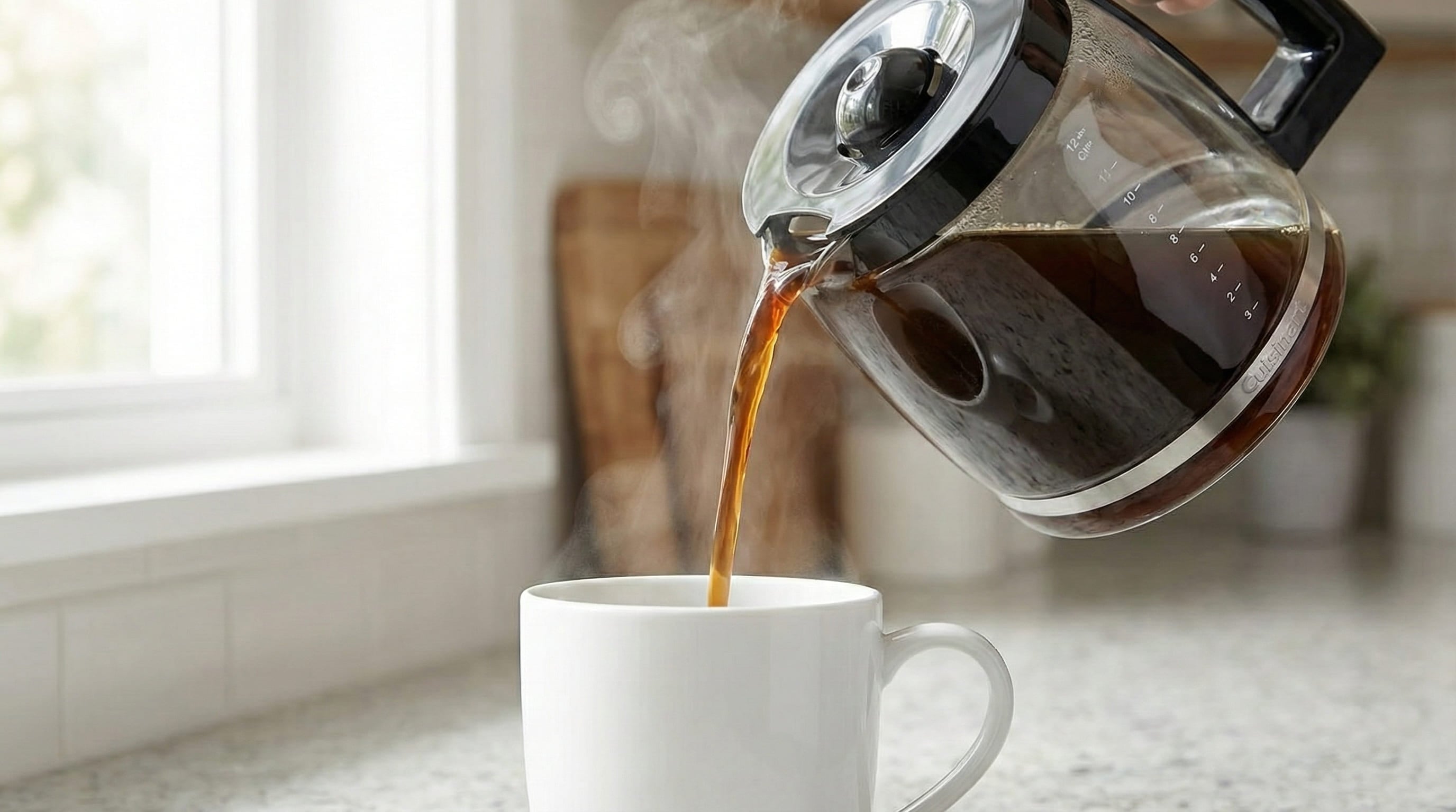 Pouring fresh brewed precision coffee from Cuisinart automatic grind brew glass carafe into ceramic mug