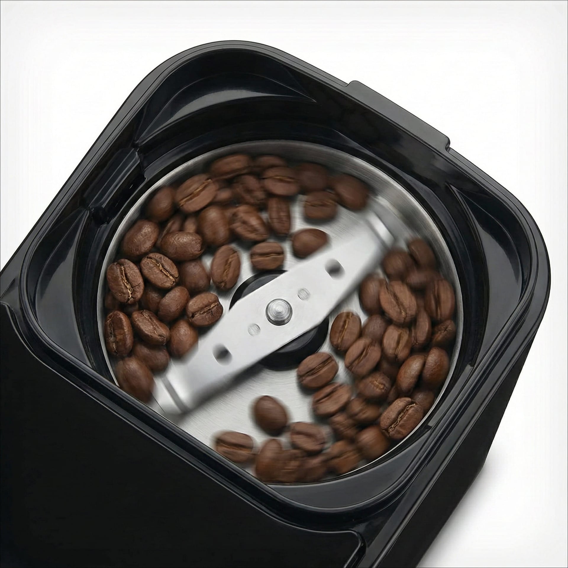 Blade grinder mechanism in bean hopper compartment of automatic grind brew system showing freshly ground coffee preparation