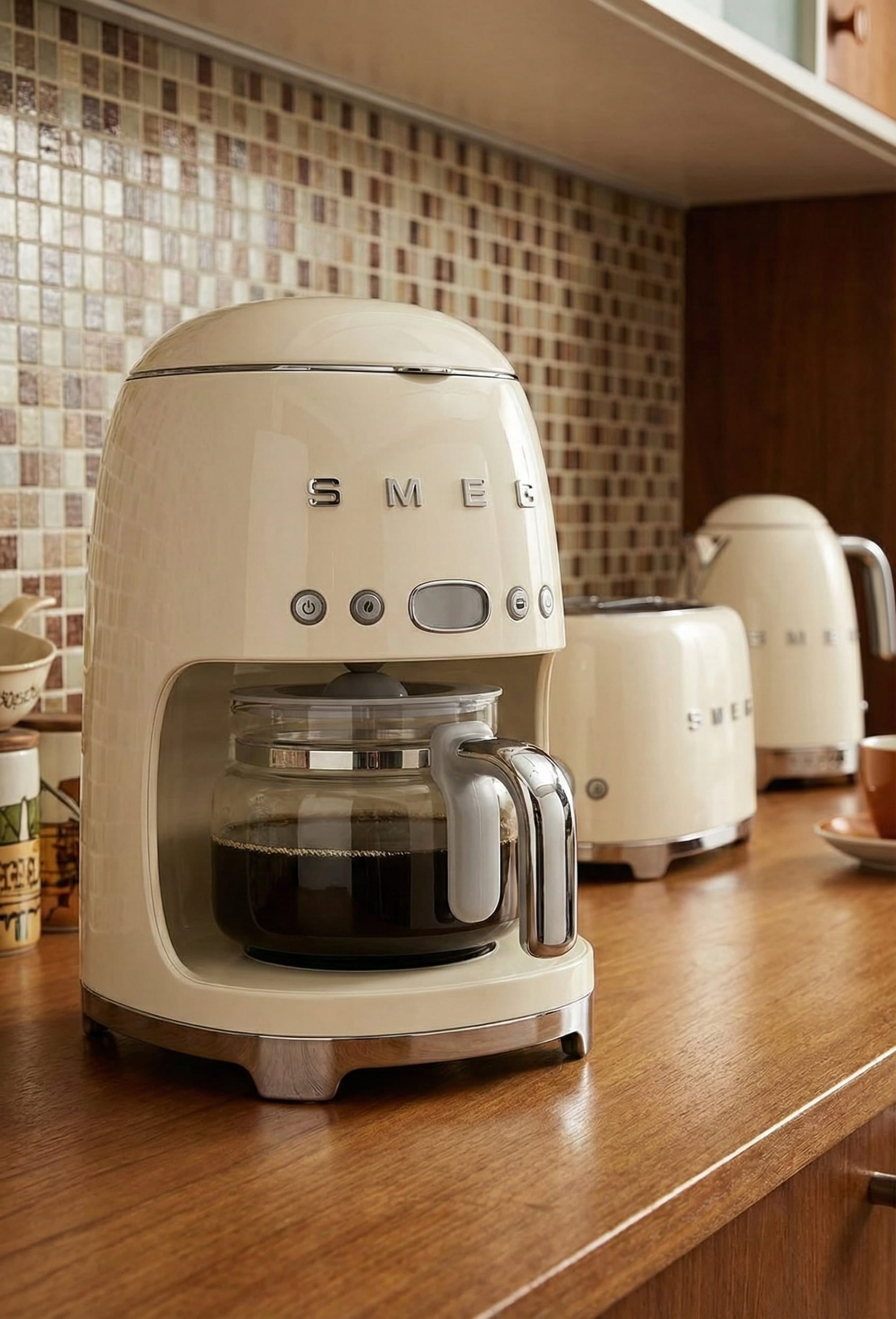 Smeg coffee maker retro aesthetic with glossy cream finish stainless steel body and chrome '50s style detailing perfect for mid-century modern kitchens