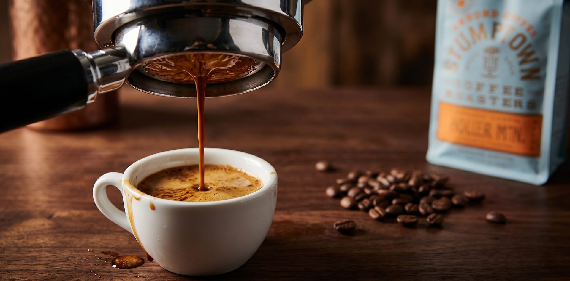 Stumptown Holler Mountain espresso shot being pulled from bottomless portafilter showing rich dark crema in white demitasse cup