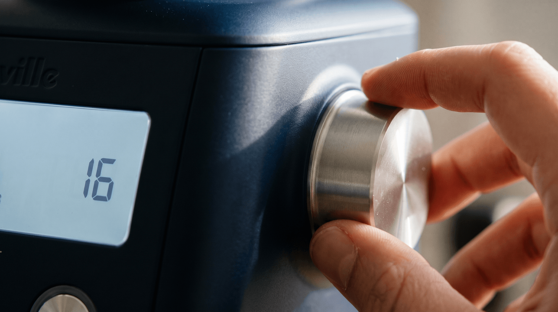 Close-up of a stainless grinder's grind size dial and display showing a fine espresso setting