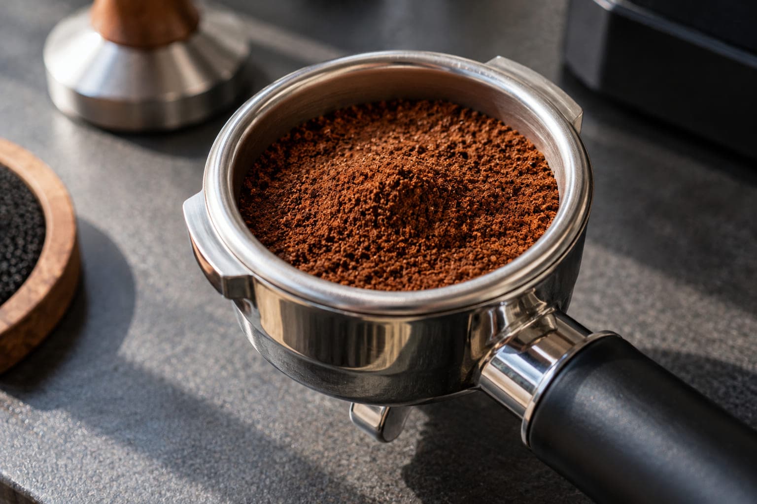 Portafilter basket filled with ground coffee, showing dose level relative to the basket's rim