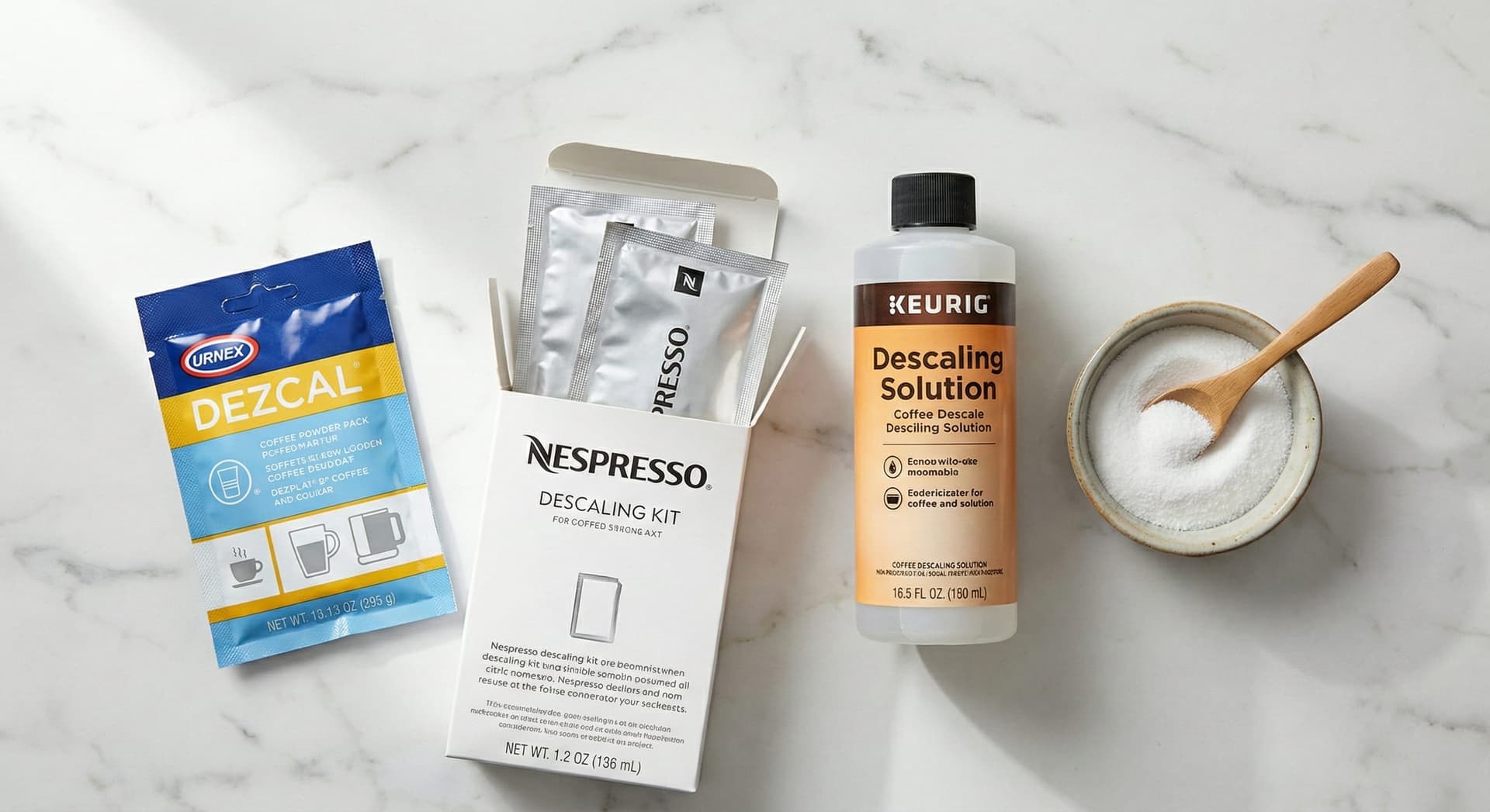 Flat lay of four coffee machine descaling products: Urnex Dezcal powder packet, Nespresso descaling kit sachets, Keurig descaling solution bottle, and a bowl of white food-grade citric acid powder—comparison of best coffee machine descalers