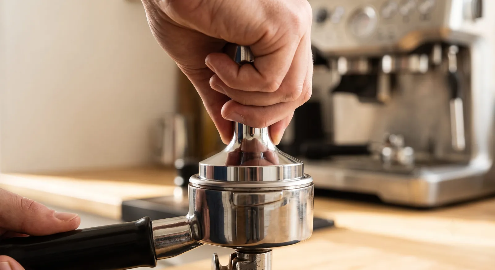 Hand pressing a tamper level into a portafilter basket