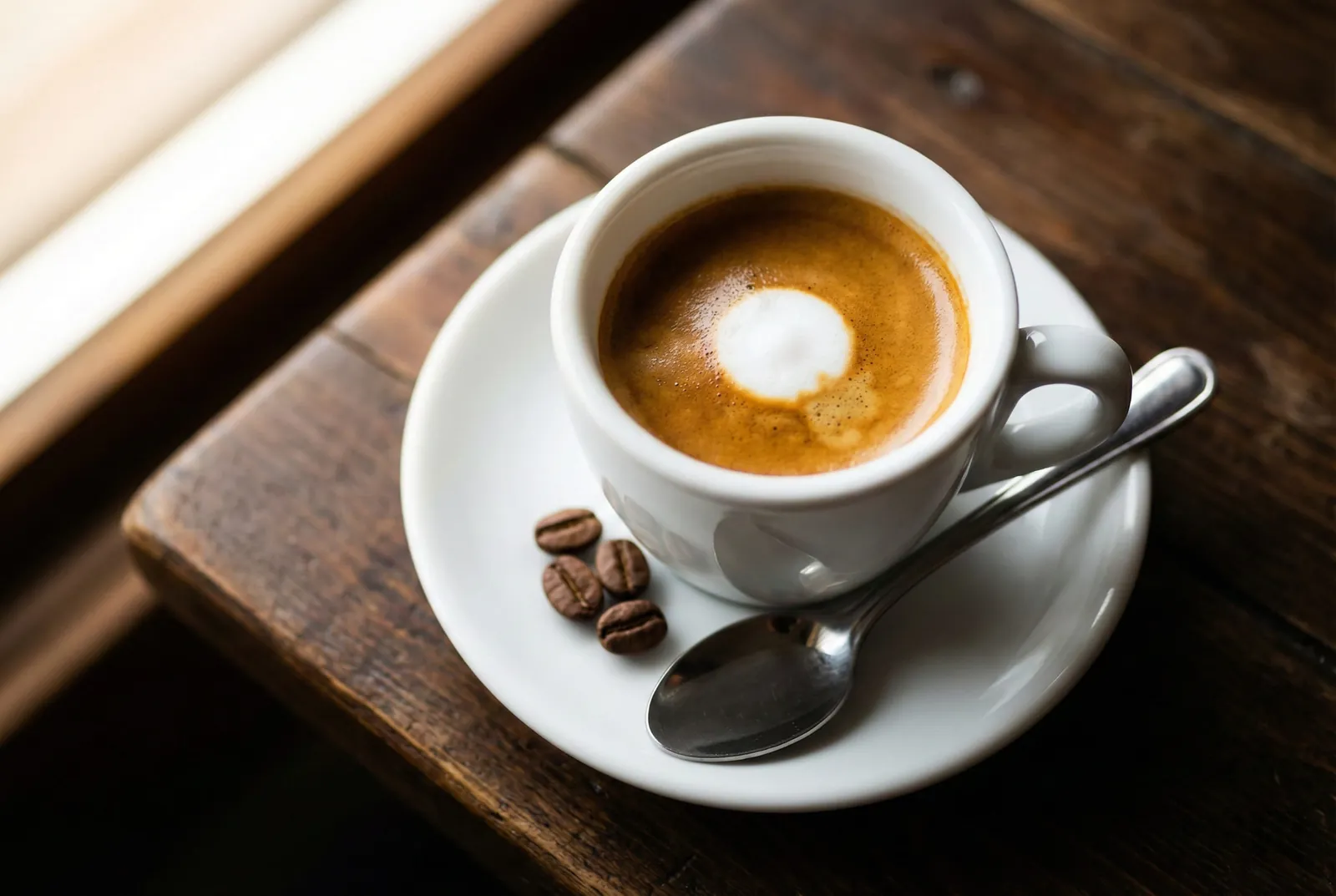 Espresso macchiato with a small dot of milk foam in a white cup on a saucer