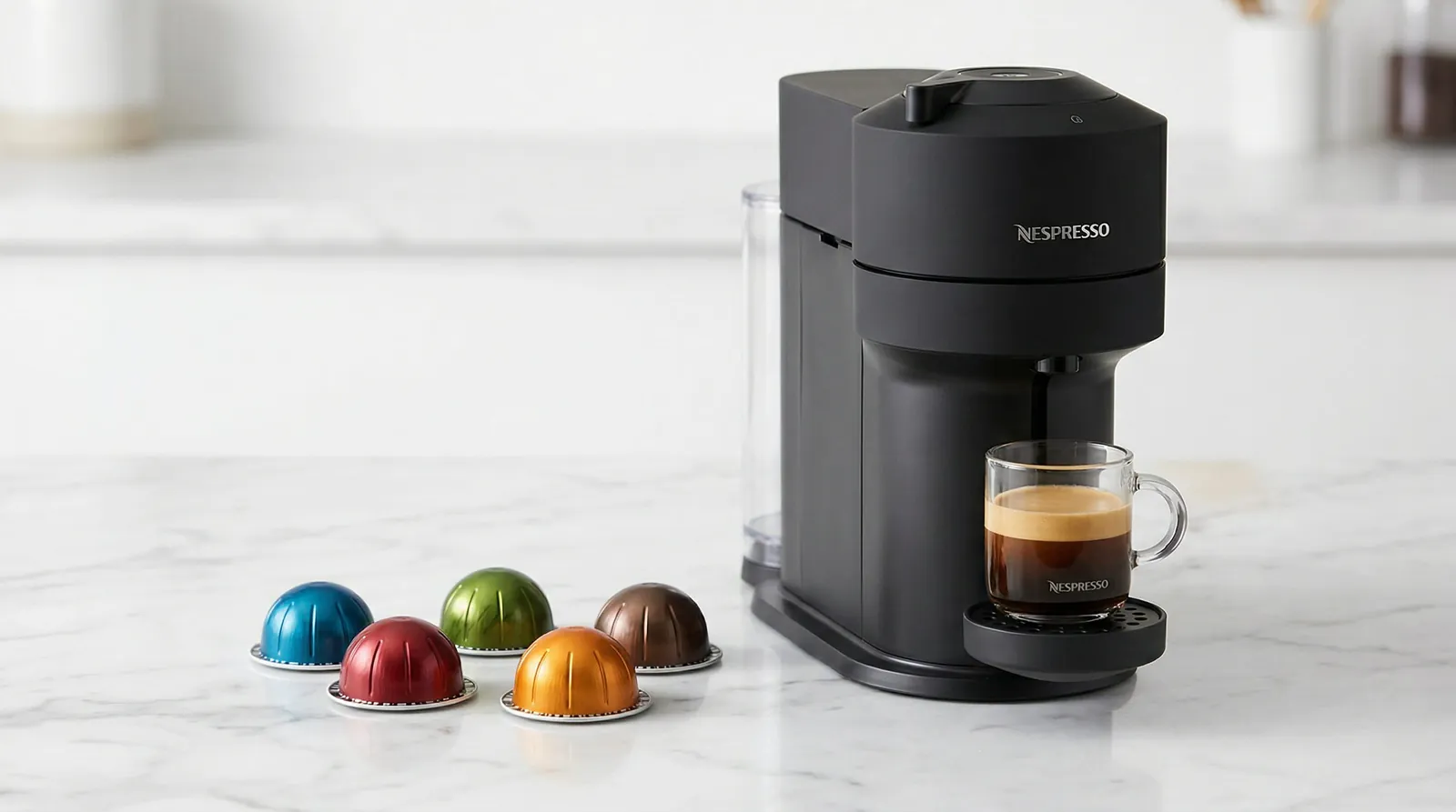 Dark Nespresso Vertuo machine with a glass of coffee under the spout and colourful dome-shaped Vertuo capsules beside it