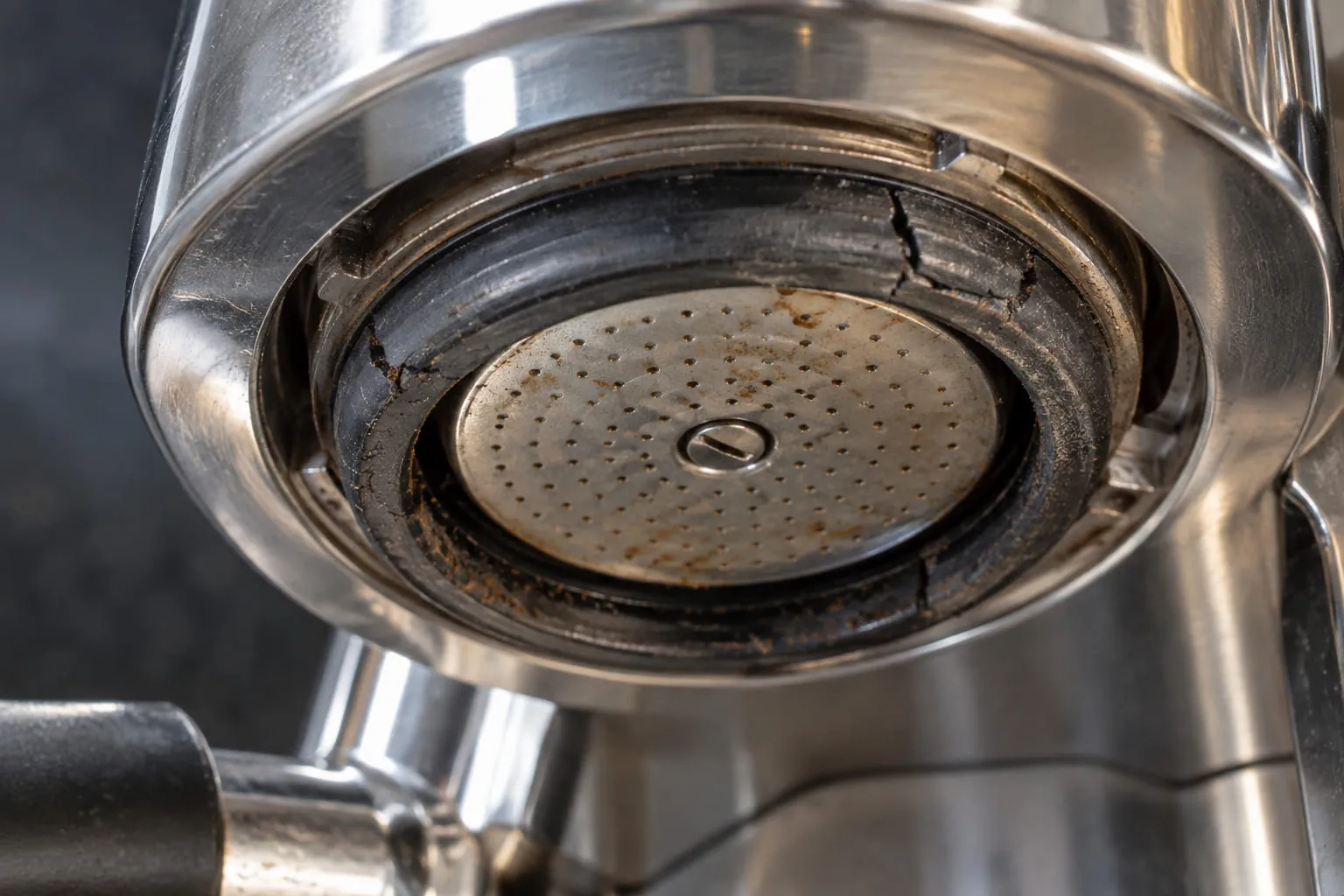 Close-up of a portafilter group head with a visibly worn, cracked rubber gasket ring
