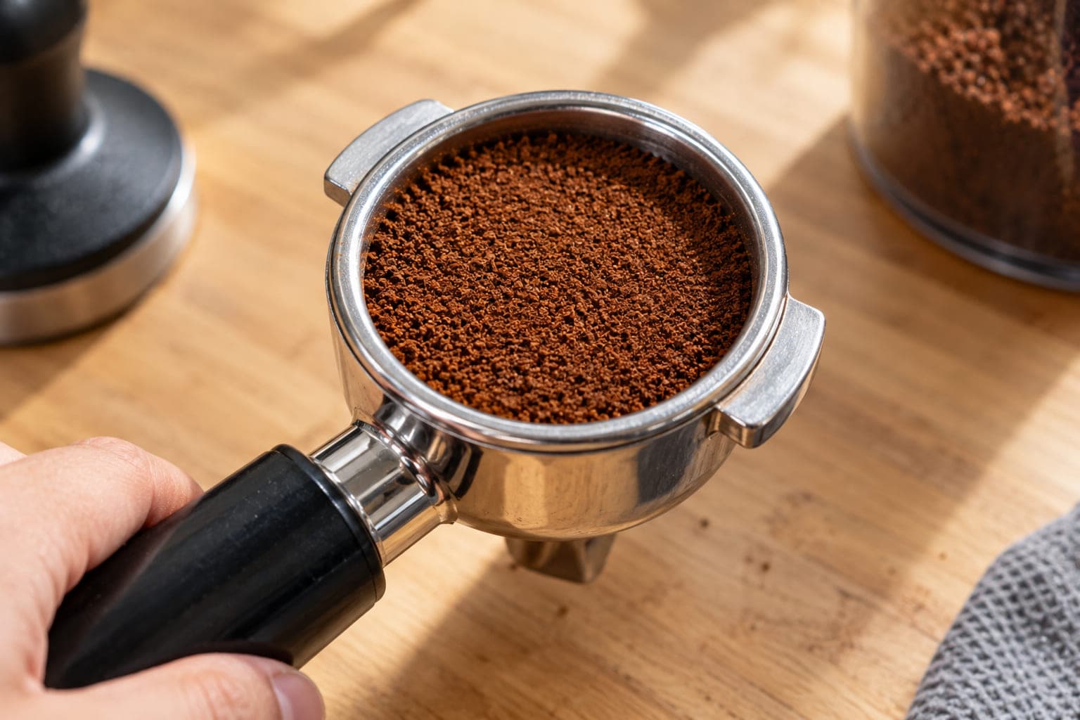 Portafilter basket filled with evenly leveled, freshly distributed coffee grounds before tamping — proper distribution technique to prevent channeling and sour espresso