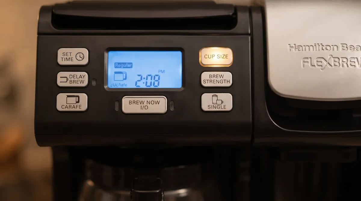 Coffee maker control panel with a backlit display and buttons for cup size and brew strength