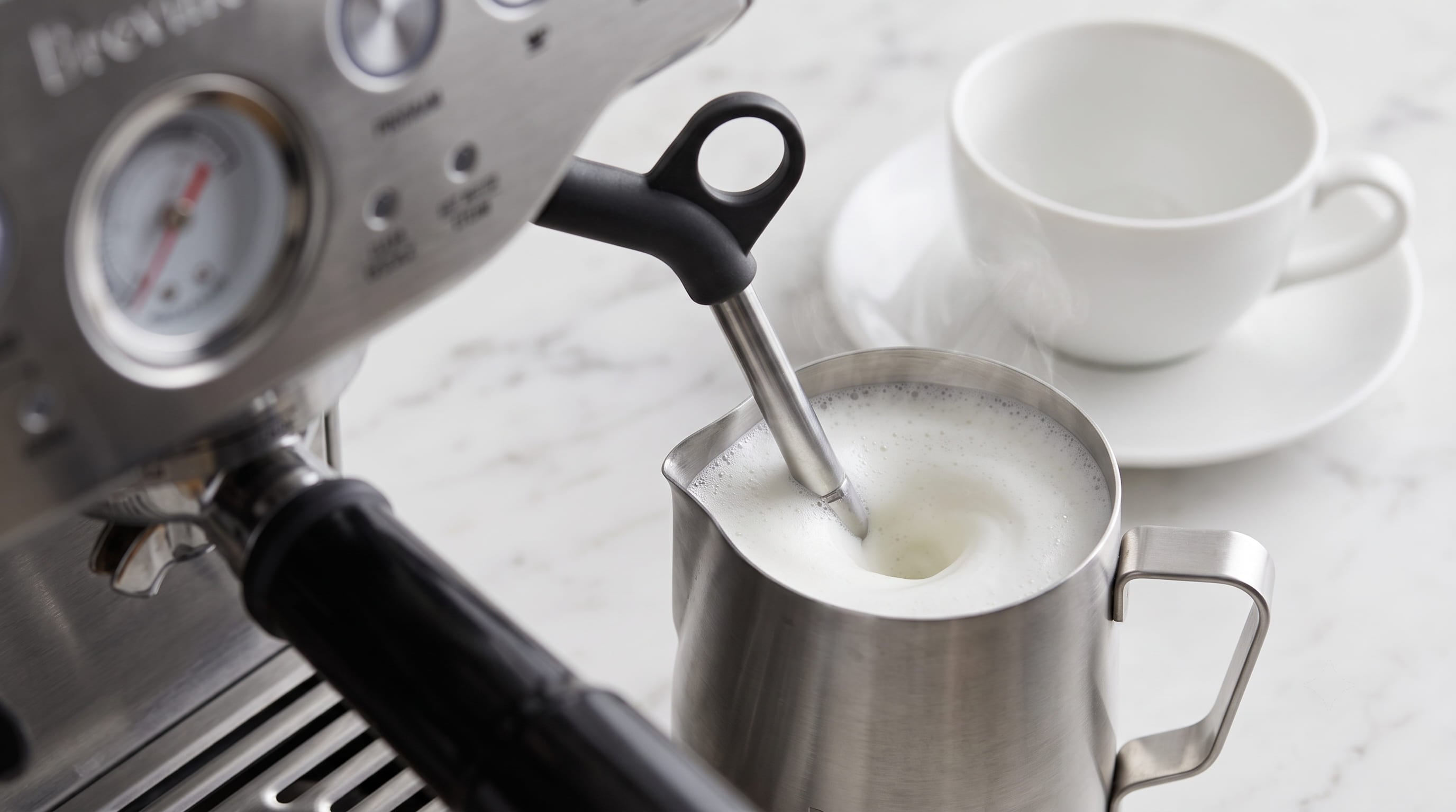 Breville Barista Express BES870XL manual steam wand frothing whole milk in stainless steel pitcher for cappuccino or latte