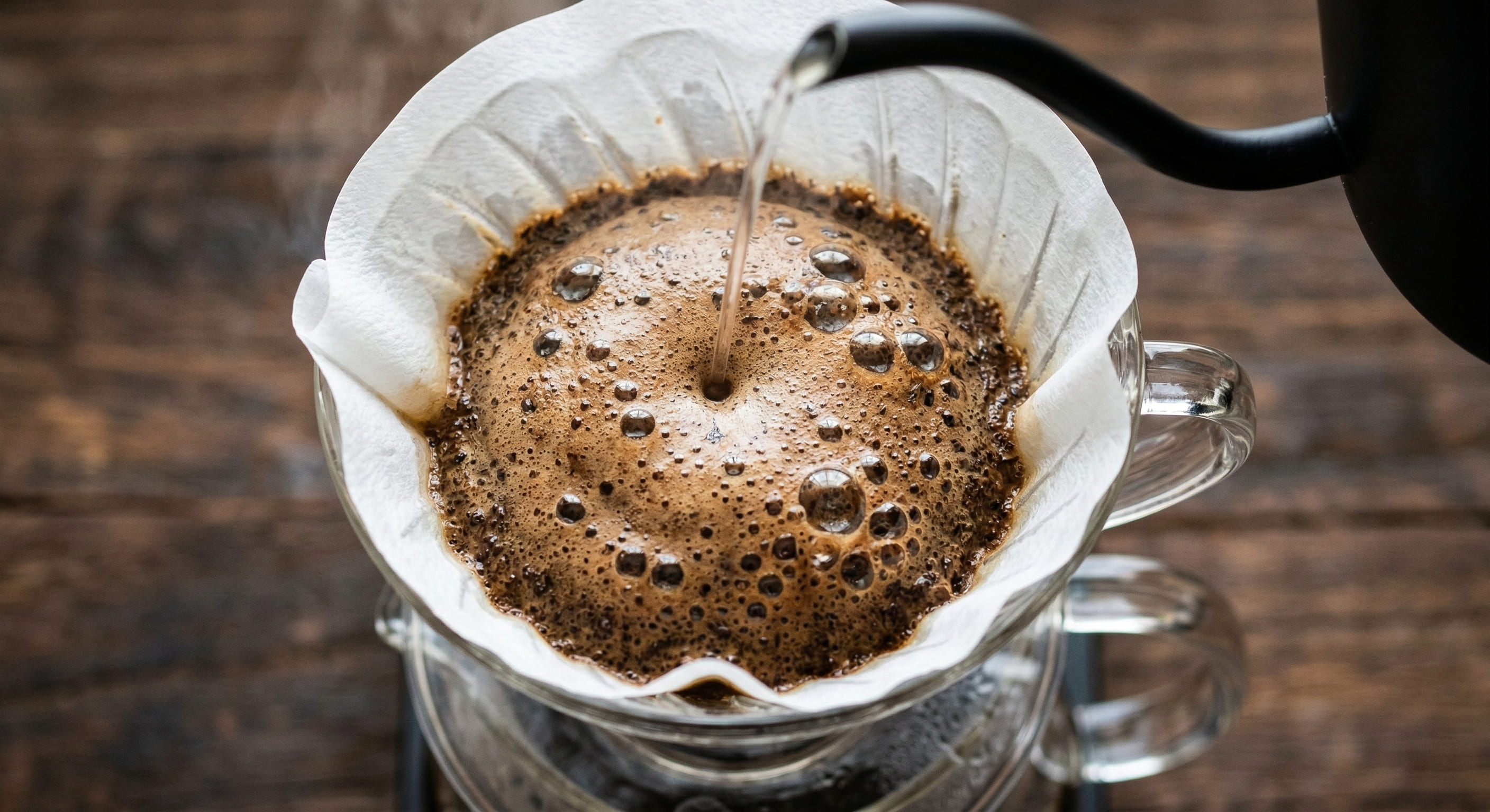 V60 pour over coffee bloom phase — coffee grounds expanding with CO2 bubbles during the 30-second pre-infusion bloom step