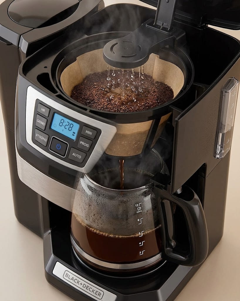 Hot water dripping through filter basket into glass carafe during active brewing cycle of BLACK+DECKER programmable coffee maker