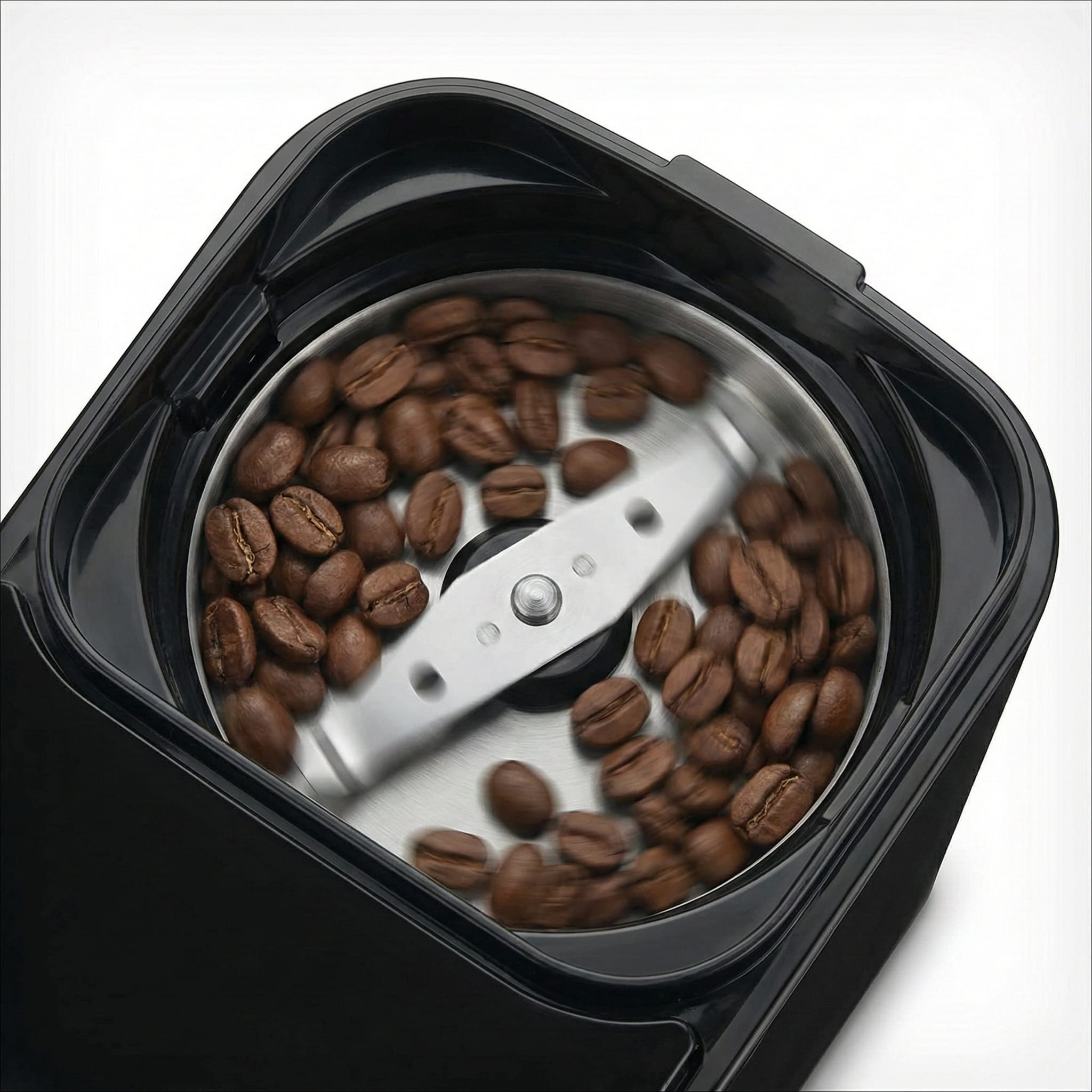 Blade grinder mechanism in bean hopper compartment of automatic grind brew system showing freshly ground coffee preparation