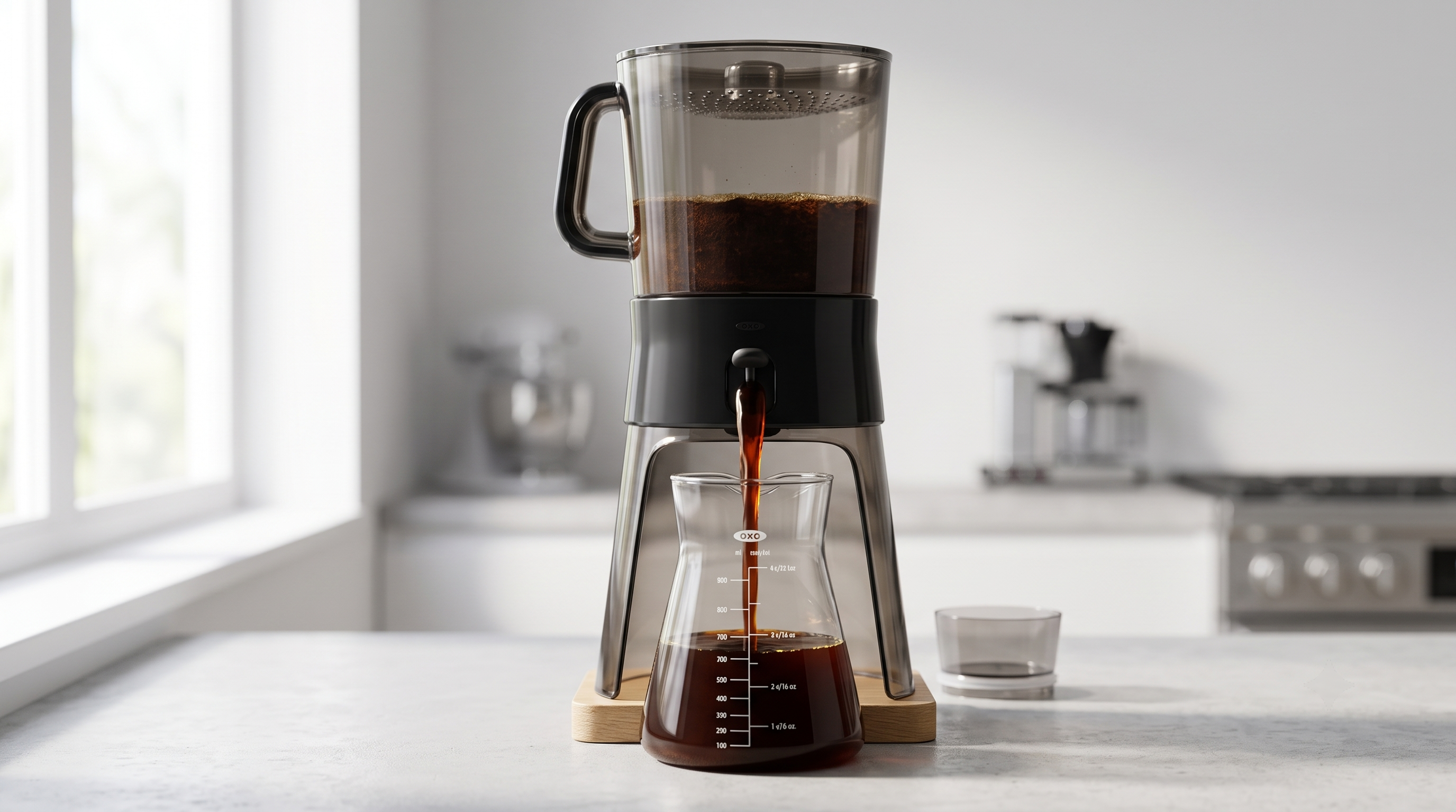 Cold brew concentrate flowing through OXO tap into glass carafe — dark rich concentrate from OXO Good Grips cold brew maker