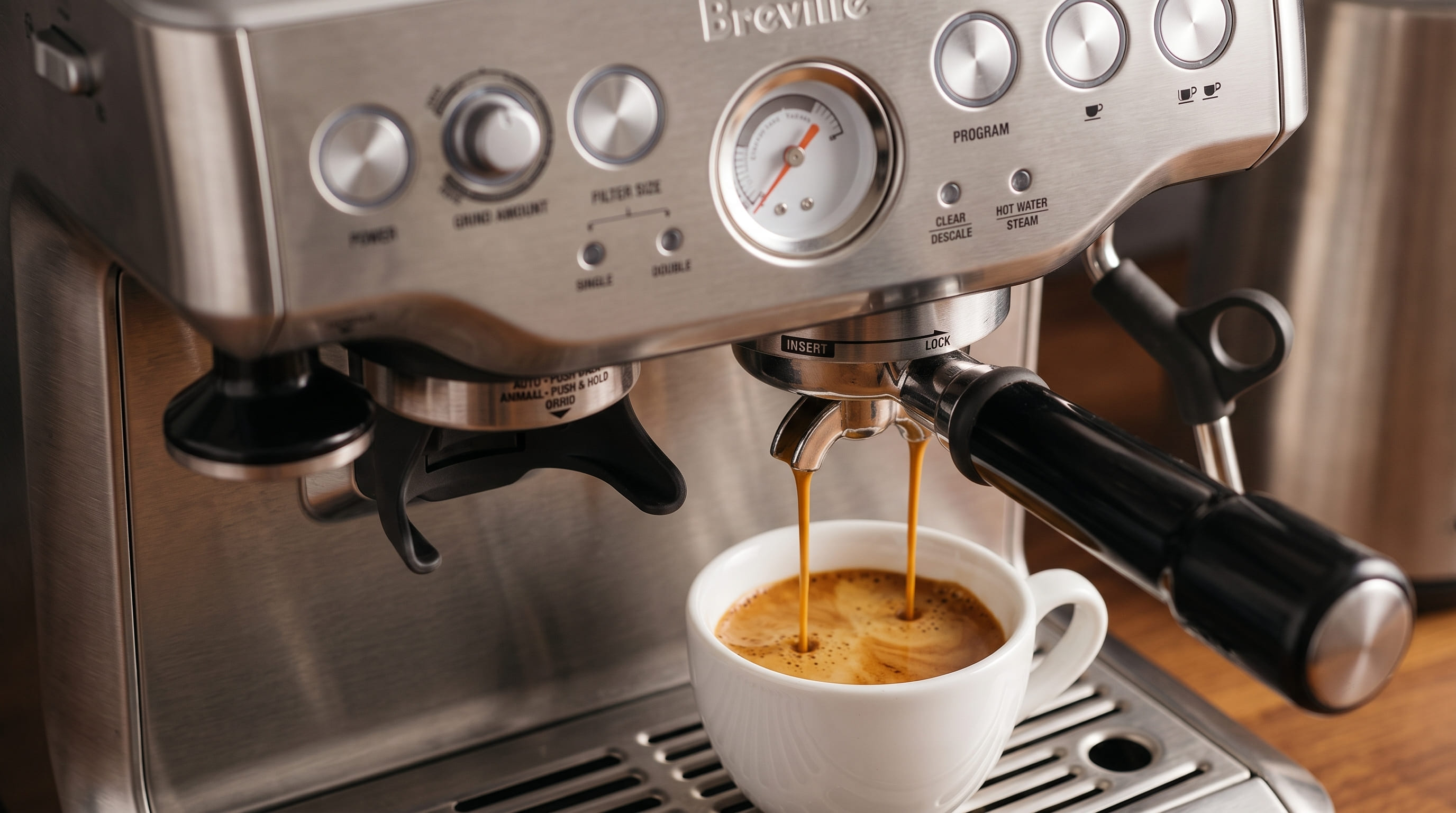 Breville Barista Express BES870XL pulling a double espresso shot with crema into a white ceramic cup — pressure gauge visible at 9 bar