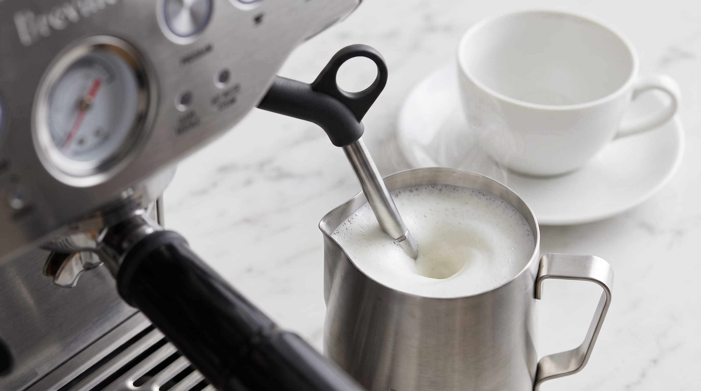Breville Barista Express BES870XL manual steam wand frothing whole milk in stainless steel pitcher for cappuccino or latte